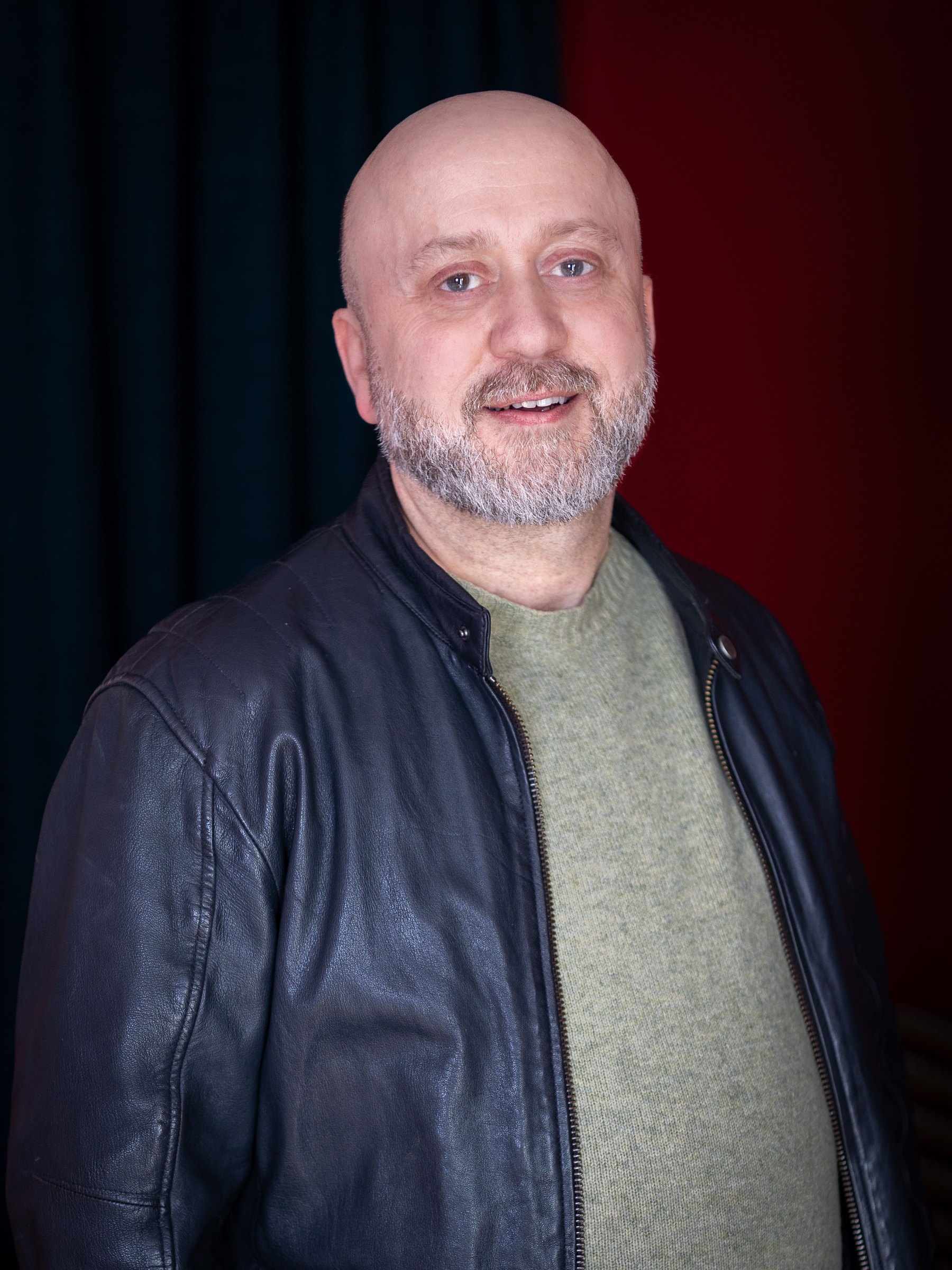 Damian Dudkiewicz, smiling, in a black leather jacket